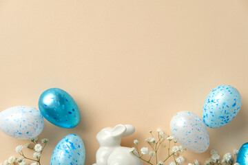 Easter flat lay composition with ceramic white bunny, speckled blue eggs, and soft white blooms on...