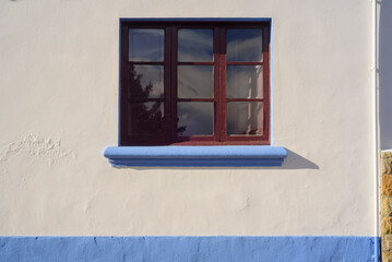 Ventana en fachada de casa rural pintada de blanco y azul