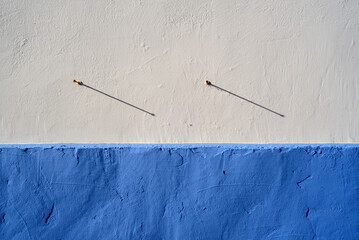 Sombra de clavos en fachada blanca y azul
