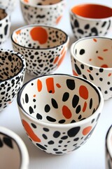 Artistic ceramic bowls with black and orange abstract patterns on a white surface in a bright studio shot showcasing craftsmanship and modern design