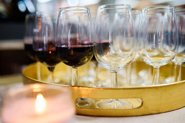 Close-up of glasses filled with white and red wine on a golden tray, ready for serving at an elegant event or celebration