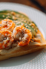 Shrimp waffles on a fork at a wooden table