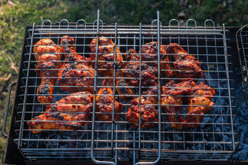 high angle view of chicken legs in a grill grate above charcoal grill