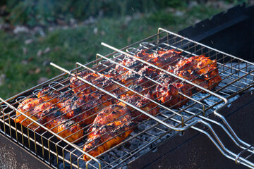 close up view of chicken legs in a grill grate above charcoal grill