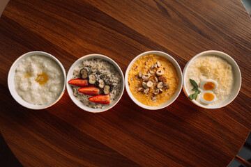 4 types of porridge in white bowls on a wooden background, oatmeal, corn, millet and rice