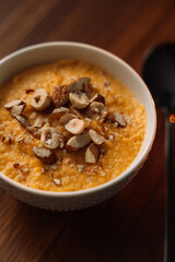 corn porridge with nuts in a white bowl, vertical photo