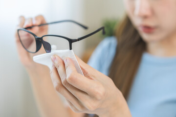 Cleaning glasses concept, hand of asian young woman hand holding frame of glass, using tissue paper...