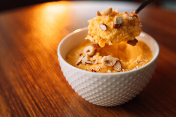 corn porridge with nuts on spoon in a white bowl