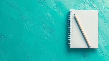 A blank spiral notebook with a wooden pencil on a textured turquoise background. A minimalistic workspace concept for creativity, planning, and organization.