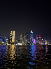 Doha skyline by night in Doha, view from a boat at the corniche