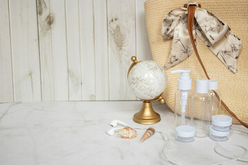 Travel essentials layout on a marble background, including items like bottles, passport, tickets, and travel accessories.