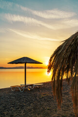 Sunrise on the Beach in the Aegean Sea, Greece with Umbrellas and Sunbeds