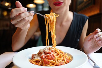A woman is eating spaghetti with a fork