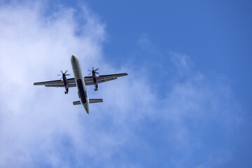 Airplane  in blue sky with light clouds over the house