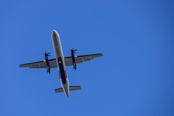 Airplane  in blue sky with light clouds over the house