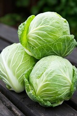 Fototapeta premium Fresh green cabbages stacked on a wooden table, showcasing their vibrant color