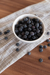 Brown ceramic bowl of fresh ripe blueberries on kitchen table