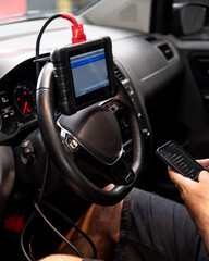 Un técnico automotriz utilizando una herramienta de diagnóstico montada en el volante dentro del interior moderno de un automóvil, realizando pruebas de sistemas del vehículo
