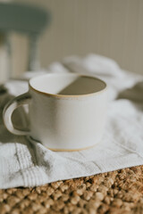 A white coffee cup sits on a white cloth. The cup is empty and the cloth is brown
