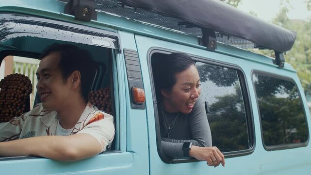 Group of professional travelers in minivan just parked near drive-in cafe, beautiful Asian woman looking out of window and taking lunchboxes