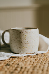 A white coffee mug with a brown background. The mug is sitting on a rug