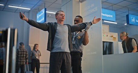 Security Checkpoint in Airport Terminal: African American Security Officer Inspecting Young Man...