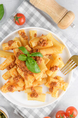 Plate of rigatoni with rich authentic Bolognese meat sauce on dinner table top view, close up
