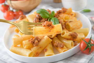 Traditional rigatoni Bolognese on fork close up