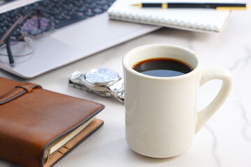 淹れたての美味しいコーヒーを飲みながら、ノートパソコンでデスクワークをしているイメージ写真
