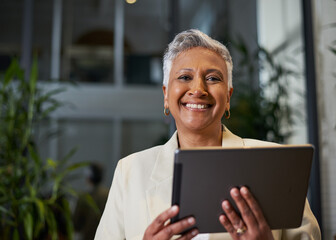 Confident Mature Businesswoman Smiling While Using a Tablet in a Modern Office Environment