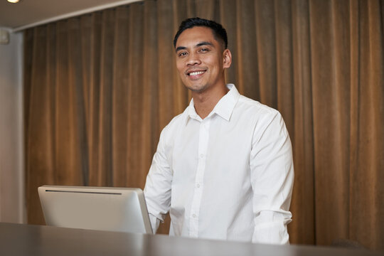 Smiling Professional in White Shirt Standing by Computer in Modern Interior