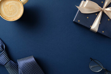 Happy Father's day concept. Flat lay composition with gift box, coffee cup, necktie and glasses on navy blue background.