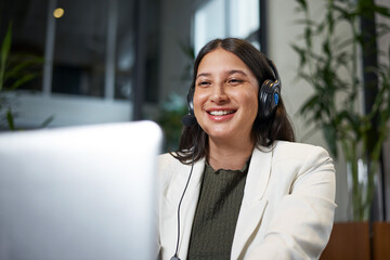 Smiling Woman in a Professional Virtual Meeting Wearing a Headset, Seated Indoors in a Bright...