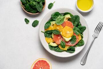 Fresh grapefruit avocado orange spinach salad in bowl. Healthy salad on gray background top view