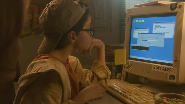 Side view of young boy looking at computer screen while downloading programs with friend in warm toned 90s setting