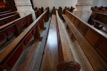 Wooden pews arranged in a quiet church in the afternoon light filtering through stained glass...