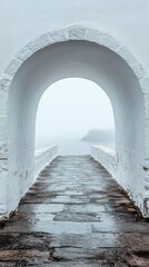 Obraz premium A serene walkway extends through a majestic white arch, guiding the viewer’s gaze toward an ocean shrouded in fog on a tranquil morning, inviting exploration and contemplation.