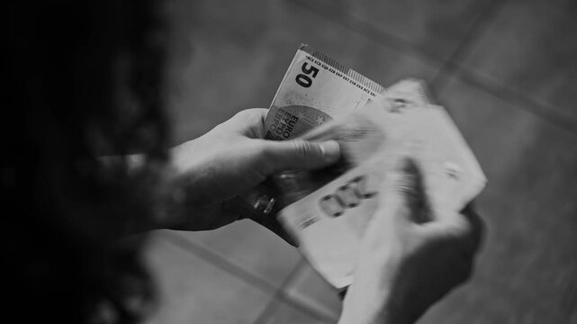Unrecognizable man counting cash, Euro bills. Black and white image. Concept of financial crime, fraud, money laundering, corruption. Financial crimes criminal liability. Documentary Footage