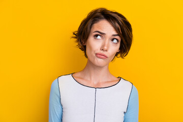 Photo of doubtful unsure lady dressed shirt looking empty space isolated yellow color background
