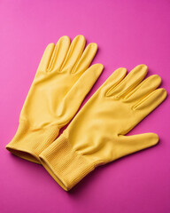 Bright yellow rubber gloves resting on a vibrant pink background, perfect for cleaning or protective tasks.