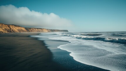Fototapeta premium Coastal Serenity: A Breathtaking Panorama of Ocean Waves Crashing on a Sandy Beach with Dramatic Cliffs Under a Clear Sky