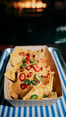 A tray of nachos with a creamy sauce and jalapenos