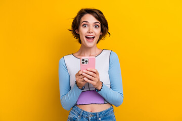 Photo of good mood excited lady dressed shirt getting message modern gadget isolated yellow color background