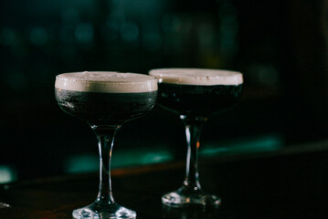 Two glasses of dark liquid on a bar
