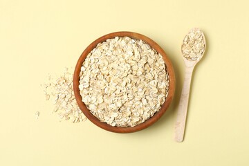 Composition with oatmeal flakes on beige background. Cooking breakfast