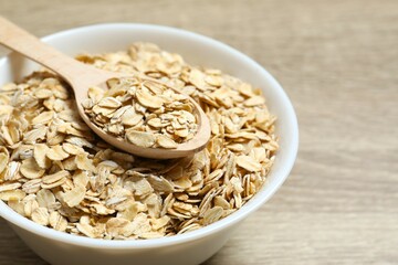 Composition with oatmeal flakes on wooden background. Cooking breakfast