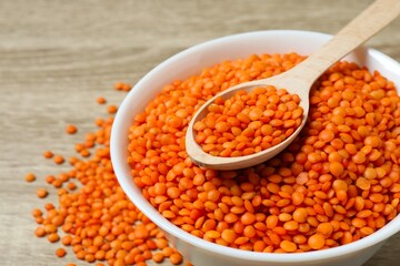 Red lentils in a spoon on a wooden background
