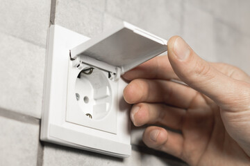 Naklejka premium Man is opening safety waterproof electricity switch socket with cover in bathroom. Close up.