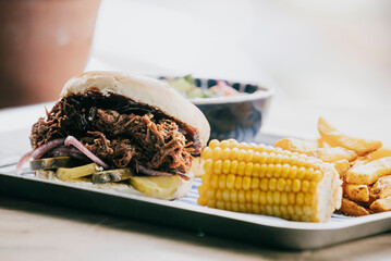 A plate of food with a sandwich, corn, and fries