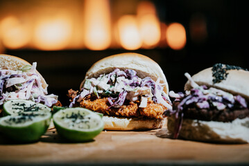 Three sandwiches with coleslaw and lime on a wooden table